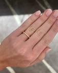 A close-up of a hand wearing a delicate yellow gold diamond band ring with small pavé-set stones