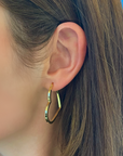 Gold hoop earring worn by a person with brown hair.