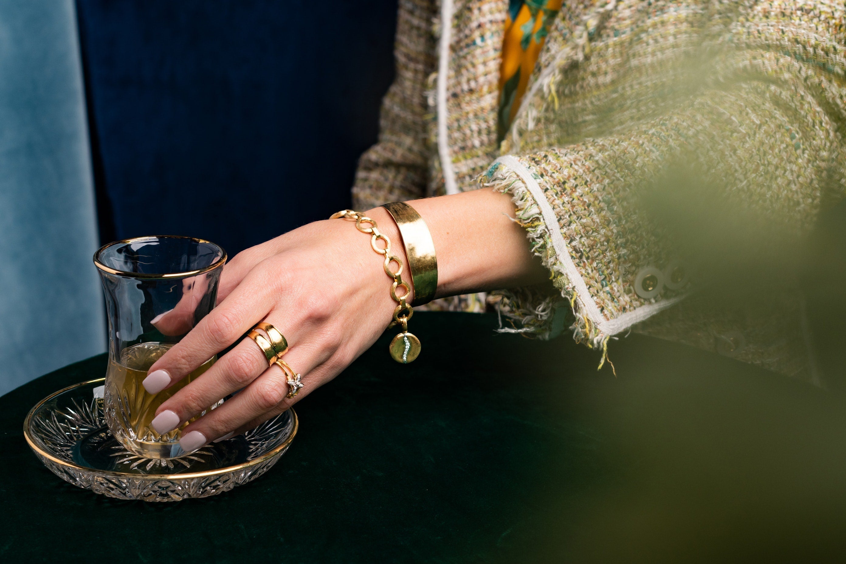 Woman reaching for a glass wearing gold jewelry