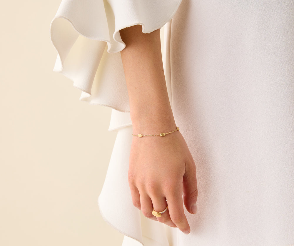 Yellow gold bracelet chain with five stations of hand engraved beads. Lobster clasp with chain extender. On a white background.