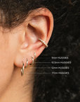 These 14k yellow gold earrings from Zoe Chicco measure 10.5mm in diameter with a hinged closure. Shown on a model with a size comparison of 9mm, 12mm, and 17 mm versions of the earring.