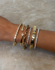 Stack of yellow gold and diamond bangles from designers Roberto Coin, Phillips House, Marco Bicego, and Brown & Co. featuring round diamonds, oval diamond, bezel set bangles, tennis bracelets, and paperclip chains