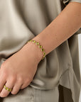 Yellow gold bracelet with bezel set peridot stones set in a line on a white background. displayed on a model.