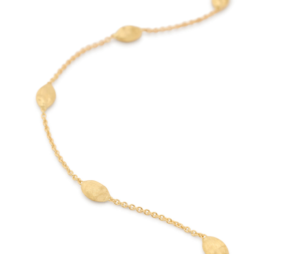 Yellow gold bracelet chain with five stations of hand engraved beads. Lobster clasp with chain extender. On a white background.