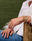14k yellow gold bangle features an open cuff design and bezel set diamonds that total 0.60ctw. Styled on a model with bracelets and rings.