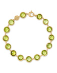 Yellow gold bracelet with bezel set peridot stones set in a line on a white background.