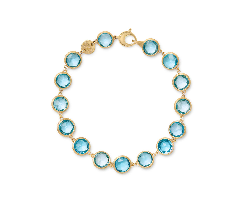 Yellow gold bracelet with bezel set blue topaz stones set in a line on a white background.