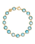 Yellow gold bracelet with bezel set blue topaz stones set in a line on a white background.