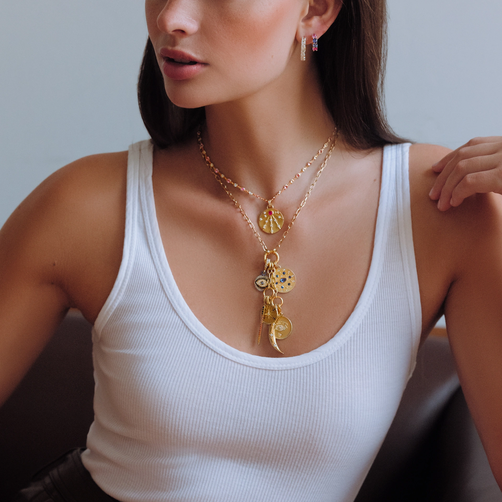 This 18K yellow gold round pendant from Penny Preville features a single round pink sapphire totaling 0.35ctw, accented by round and emerald-cut diamonds totaling 0.45ctw. The pendant is finished with a bail, allowing it to be attached to different necklaces.