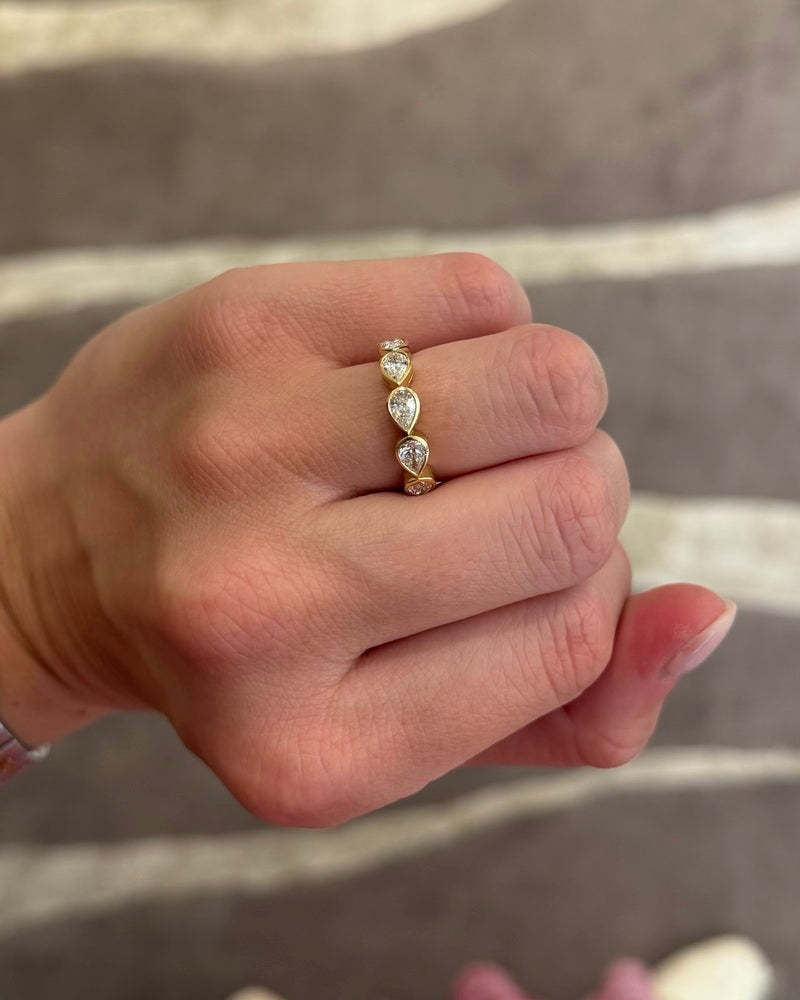 This 18k yellow gold band features five bezel set pear diamonds that total 1.01ctw. This ring measures as a size 6.5.