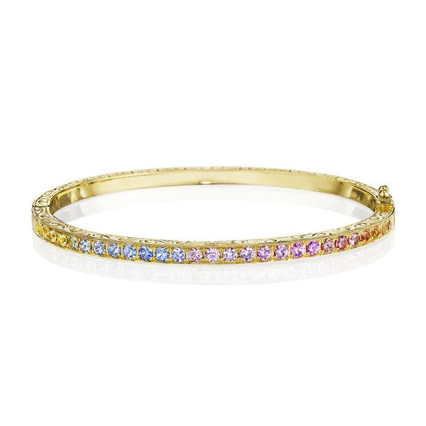 This 18k yellow gold bangle from Penny Preville features a line of round sapphires set in a rainbow color pattern that total 1.94ctw. Beautiful engraved edges surround the sapphires.