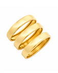 Three polished yellow gold bands arranged in a stacked, overlapping spiral design on a solid white background.