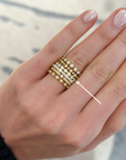 A close-up of a hand wearing a stack of multiple wedding bands from designers, Memoire, Henri Daussi, and Brown & Co., each set with diamonds. 