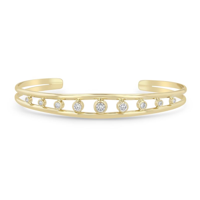 14k yellow gold bangle features an open cuff design and bezel set diamonds that total 0.60ctw. Shown on a white background.