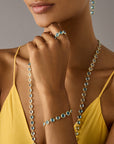Yellow gold bracelet with bezel set blue topaz stones set in a line on a model.