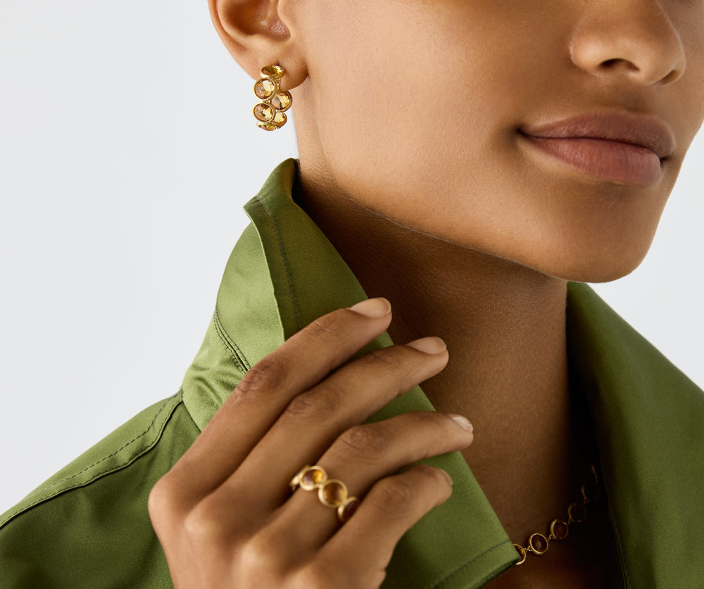 18K yellow gold hoop earrings featuring bezel-set, rose-cut round yellow quartz gemstones arranged in a continuous line. Displayed on a model.