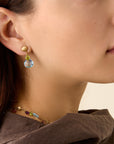 Yellow gold earrings with mixed gemstone drops from a hand engraved chain bead stud. On a model.