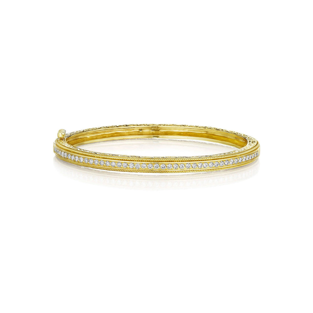 This 18k yellow gold bangle from Penny Preville features a row of round diamonds that total 0.88ctw that are set in a yellow gold bangle with engraved and twisted wire detailing.
