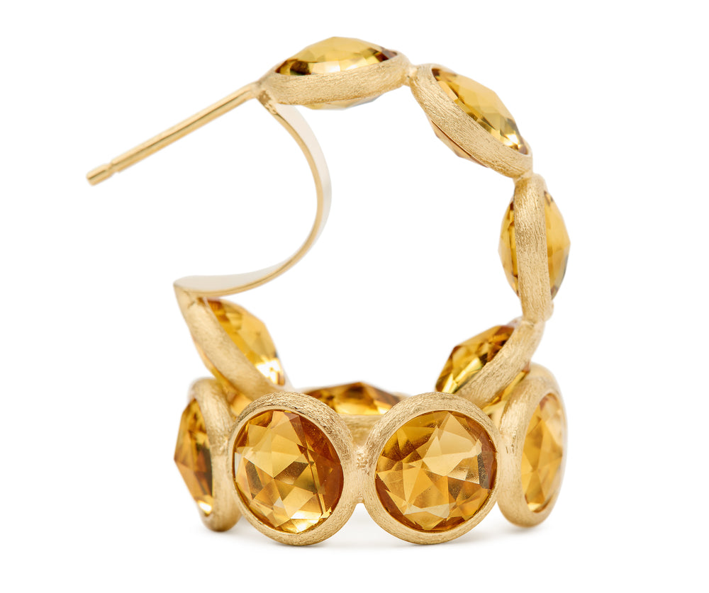 18K yellow gold hoop earrings featuring bezel-set, rose-cut round yellow quartz gemstones arranged in a continuous line. Displayed on a white background.
