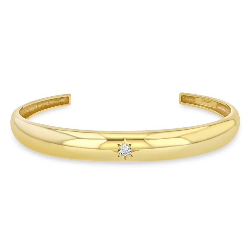 14k yellow gold cuff bracelet from Zoë Chicco features a single star-set diamond that totals 0.10ctw and at the center of the slim cuff. Shown on a white background.