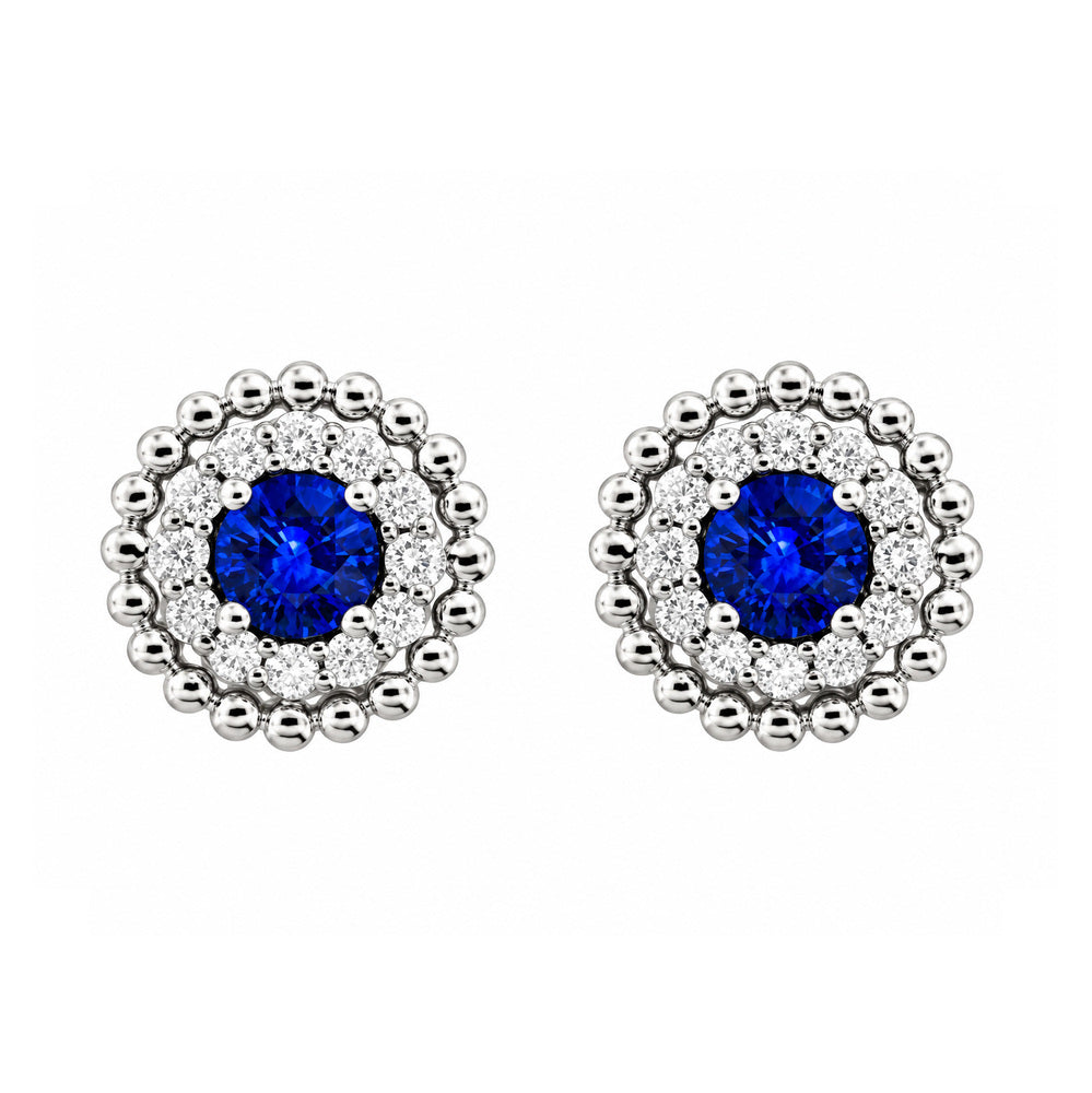 These 18k yellow gold stud earrings feature round blue sapphires at the center, surrounded by a halo of round diamonds and finished with a beaded white gold border. The sapphires total 0.44ctw, while the diamonds total 0.16ctw. The earrings are finished with post backings.