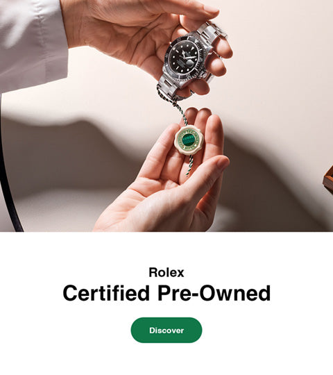 A person holds a silver-toned Rolex pre-owned watch and a small round green-and-white certificate in their hands against a clean light beige background, with text reading 'Rolex Certified Pre-Owned' and a green 'Discover' button on the right.
